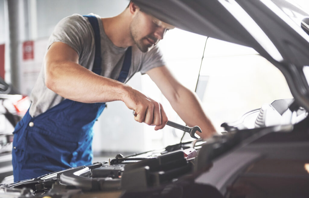 Picture showing muscular car service worker repairing vehicle.